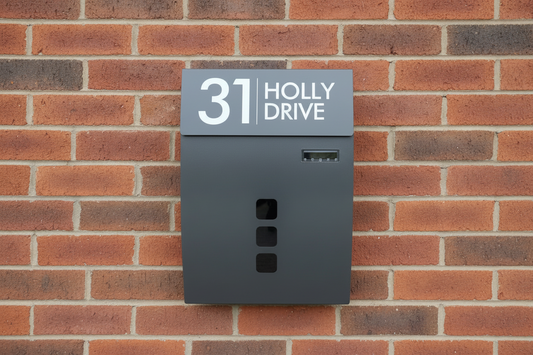 Gray mailbox with house number and name on a brick wall