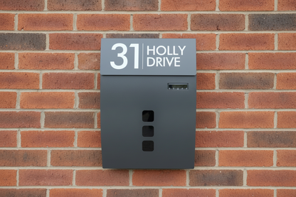 Gray mailbox with house number and name on a brick wall